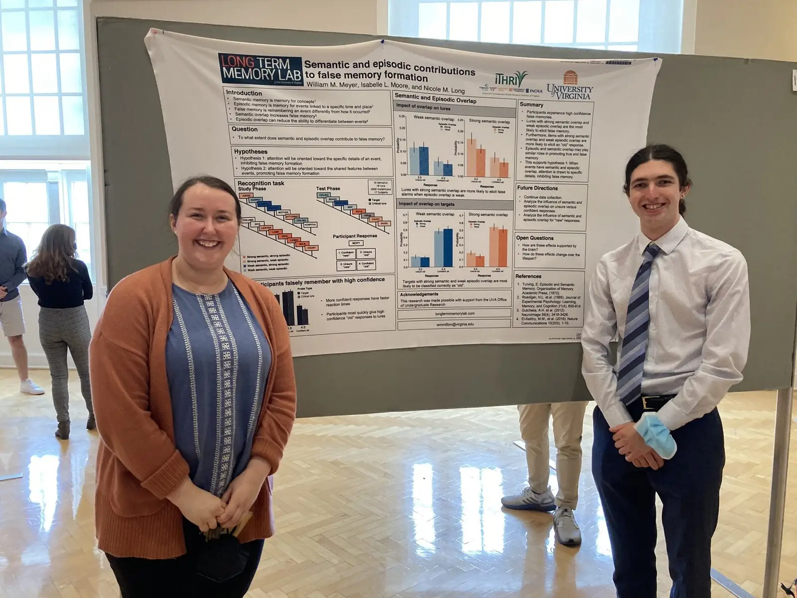 Two students beside a research poster in a university atrium