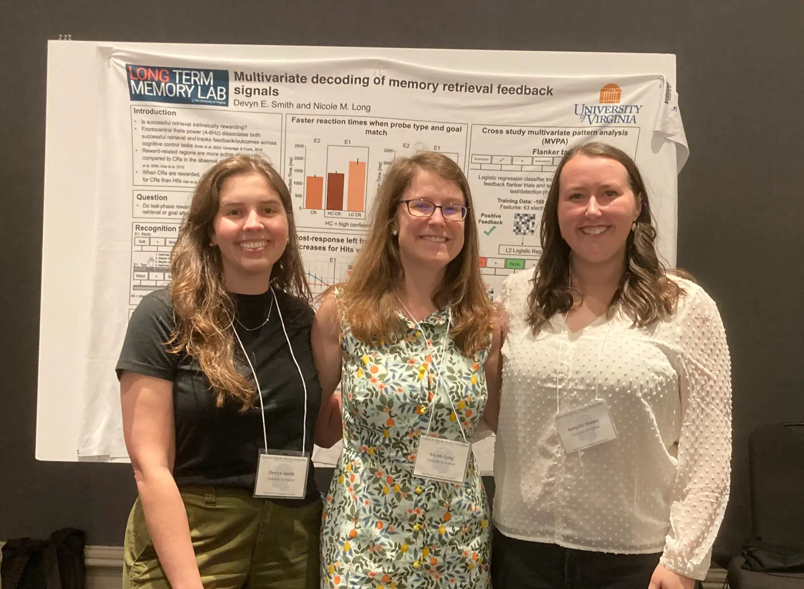 Three researchers standing beside their poster at a conference
