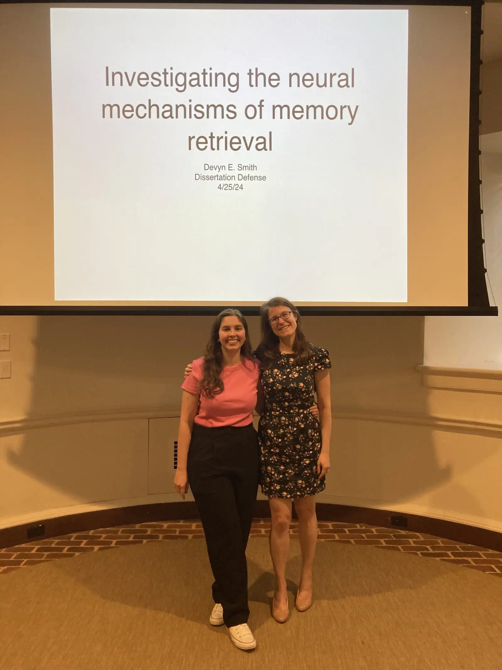 Two people standing in front of a projected dissertation title slide