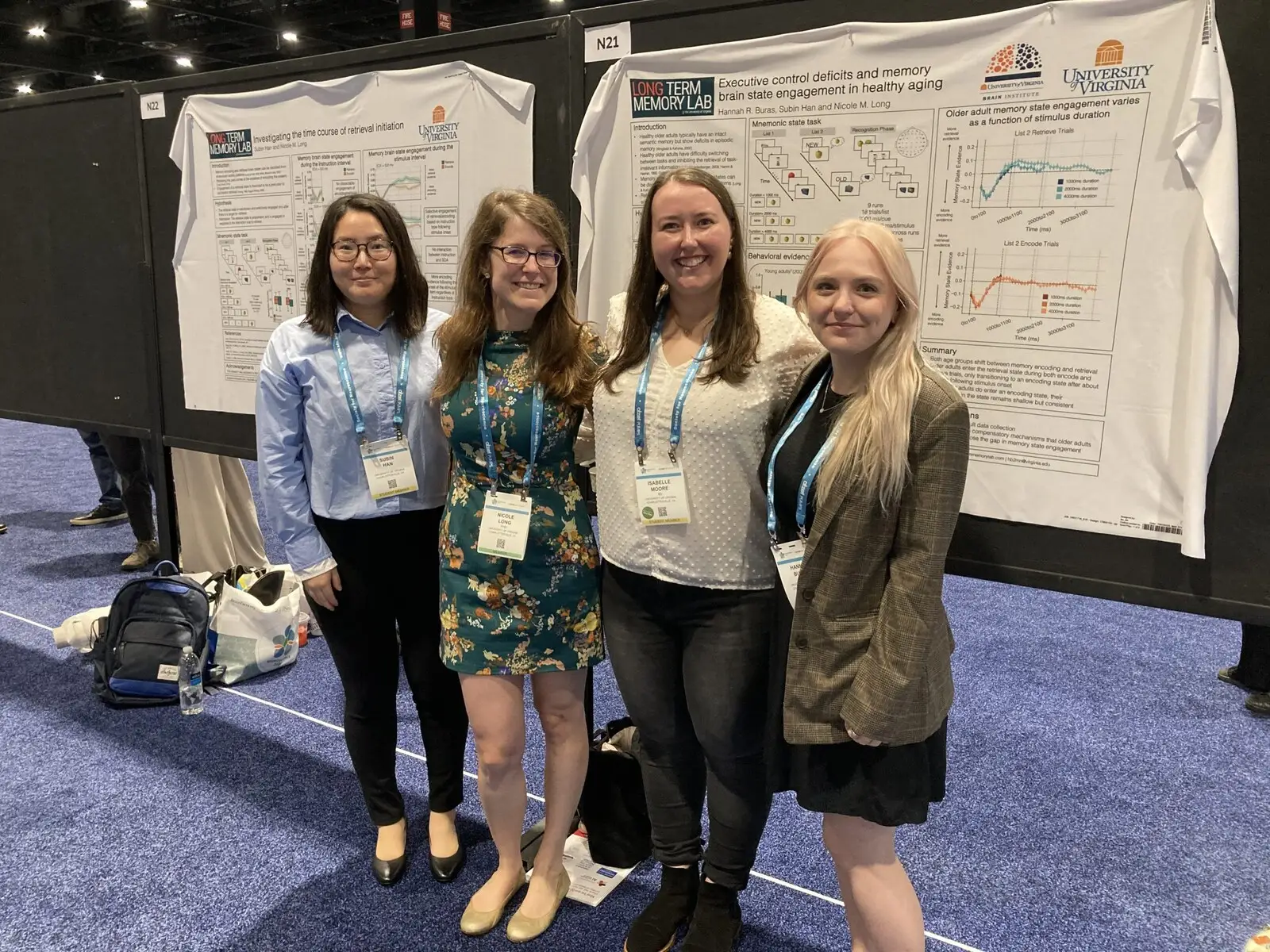 Four researchers with conference lanyards in front of two posters