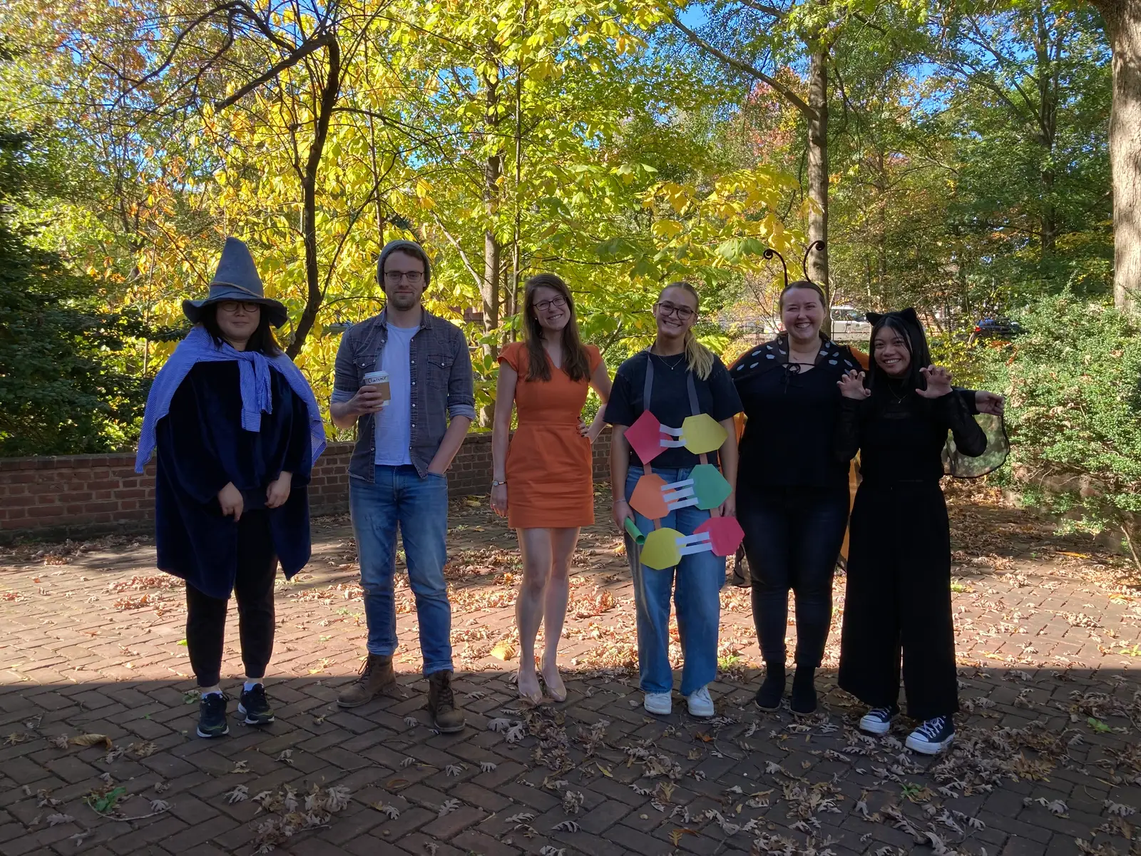 Lab members in Halloween costumes outdoors among autumn trees