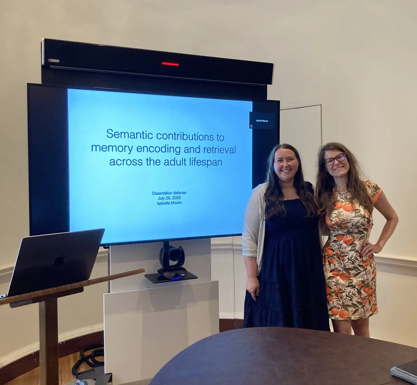 Two people in front of a screen showing a dissertation title slide