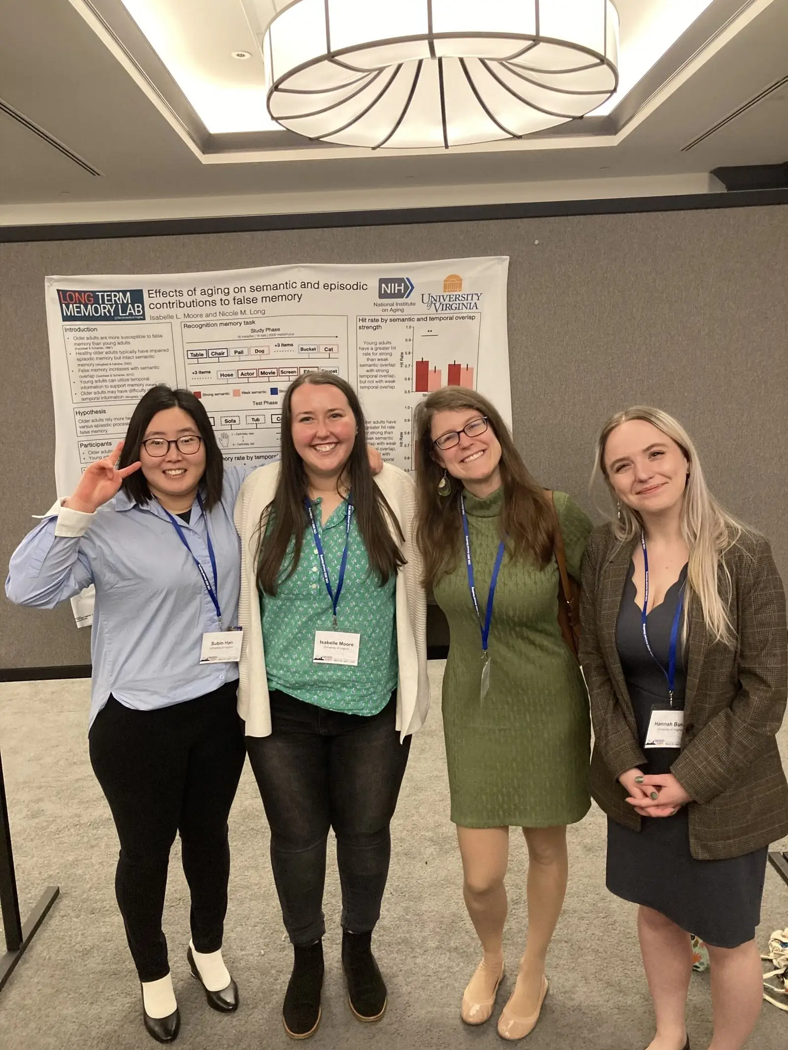Four researchers with conference lanyards standing in front of a poster