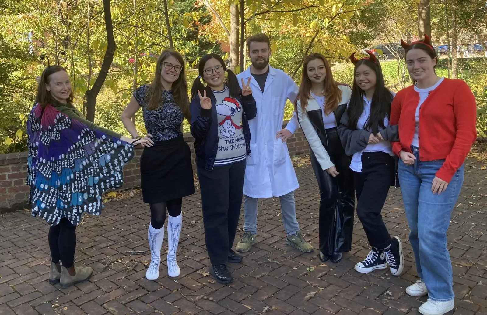 Lab members in Halloween costumes, including a lab coat, on a brick path