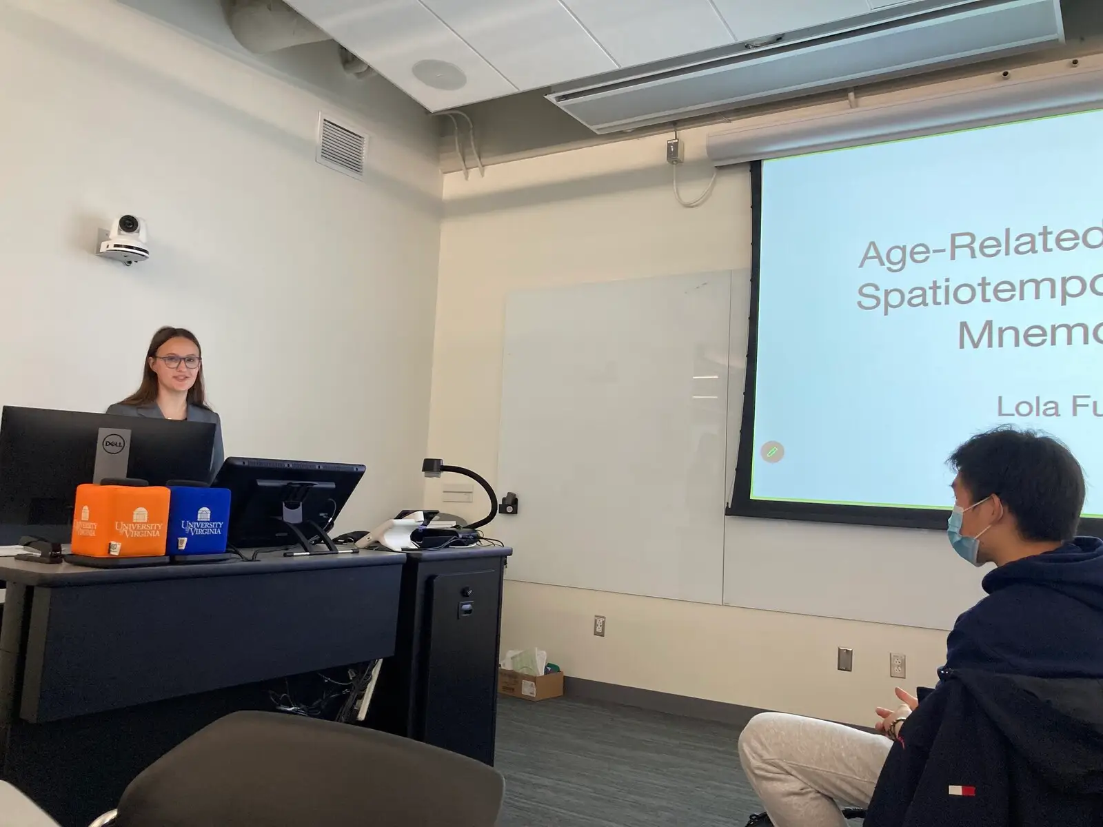 A seminar room with a projected slide about age-related spatial memory and a presenter at the desk