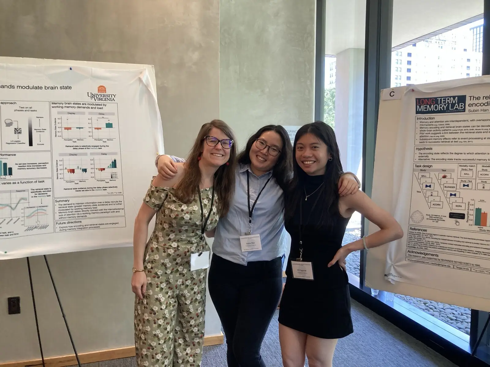 Three researchers beside a poster in a glass-walled conference space