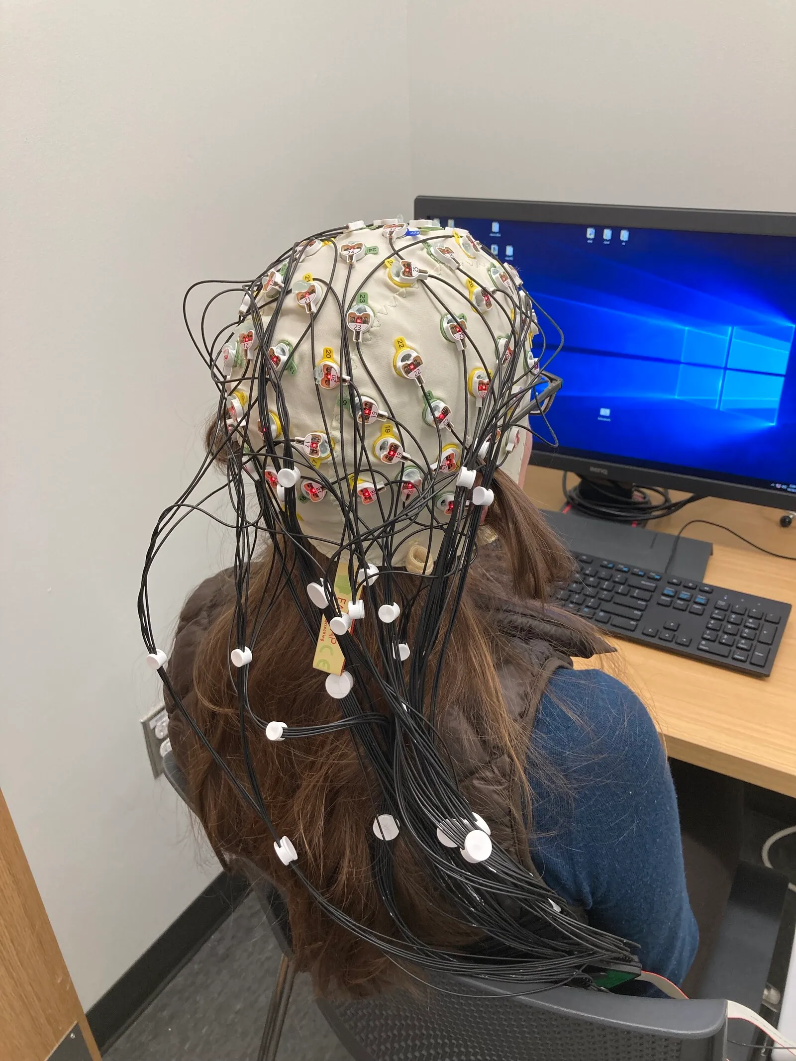 A researcher filling the electrodes of an EEG cap with water-based gel.
